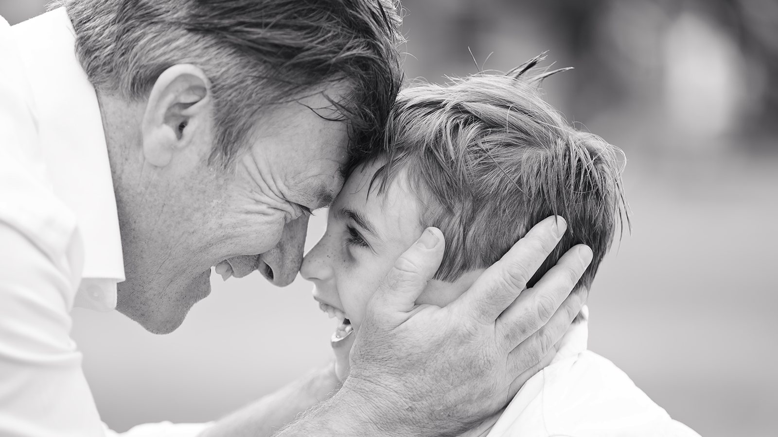 Father and son touching foreheads, black and white family portrait
