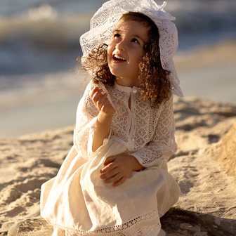 Little girl in a lace hat on the beach