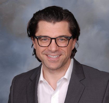 Professional headshot of a smiling man in a suit