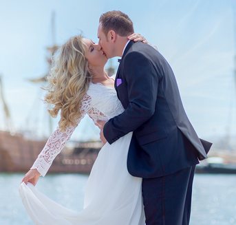Newlyweds kissing on the San Diego harbor pier
