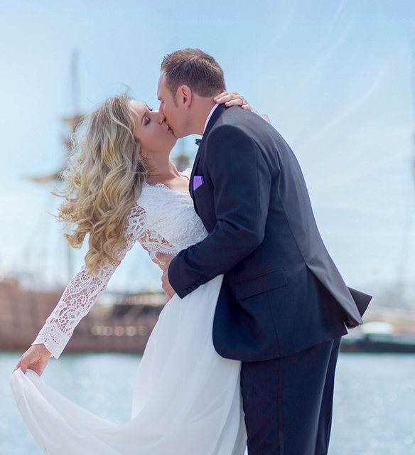 Newlyweds kissing on the San Diego harbor pier