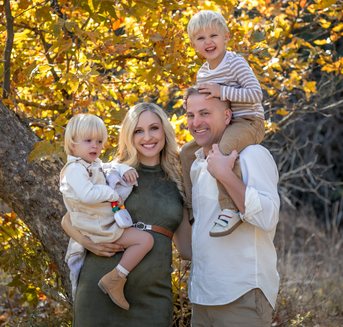 Family of four under golden autumn leaves