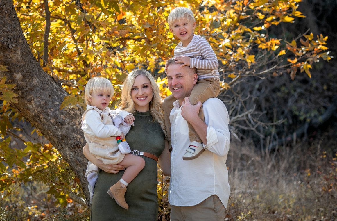 Family of four under golden autumn leaves